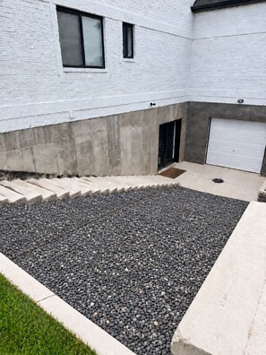 A residential building with a concrete driveway, a gravel patio, and a garage door.