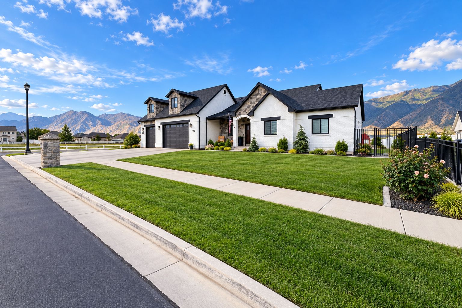 A two-story house with a well-maintained lawn, a driveway, and a mountain backdrop.