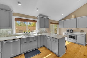 A modern kitchen with grey cabinetry, a built-in oven, and a large window with a view of the outdoors. - AC, Luxury, Comfort, Family, Hot tub, Privacy (Sunriver)