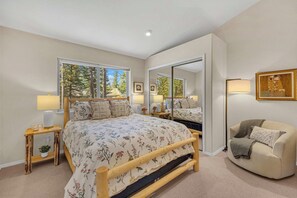 A bedroom with a large bed, bedside tables, a mirror, a sofa, and a painting on the wall. - AC, Luxury, Comfort, Family, Hot tub, Privacy (Sunriver)