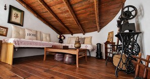 Une chambre rustique avec un plafond en bois, un lit agrémenté d’un coussin orné du mot « HOME », une table en bois et une lampe ancienne.