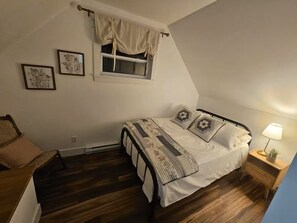 A bedroom with a bed, a nightstand, a lamp, and a window with curtains.