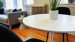 A modern living room with a round white table, a potted plant, and a sofa. - Homey 1BR Space Apartment (Chicago)