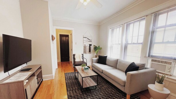 A living room with a flat-screen TV, a sofa, a coffee table, and a black rug. - Homey 1BR Space Apartment (Chicago)