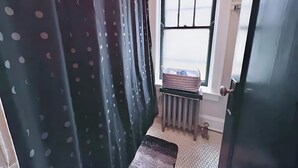 A bathroom with a window, a radiator, and a door. - Homey 1BR Space Apartment (Chicago)