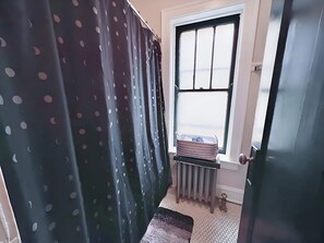 Uma casa de banho com janela, radiador e porta.