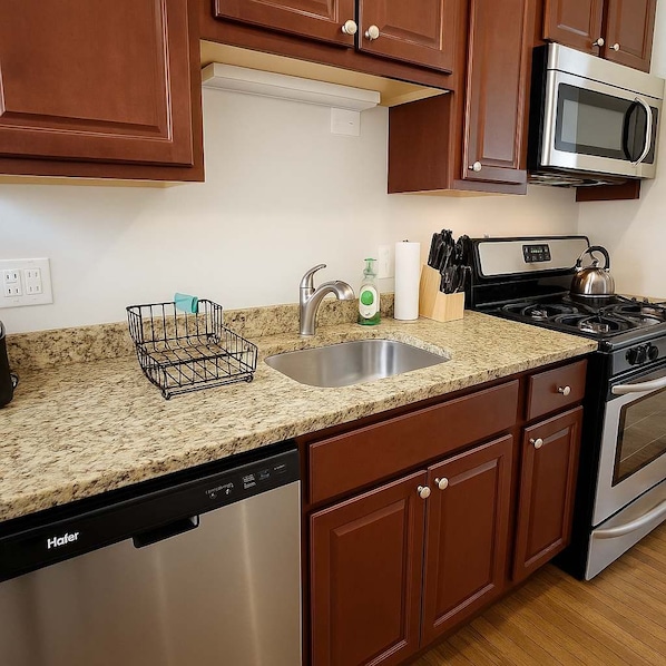 A kitchen with granite countertops, stainless steel appliances, and wooden cabinets.