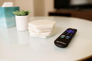 A remote control on a white table with a stack of white objects and a small potted plant.