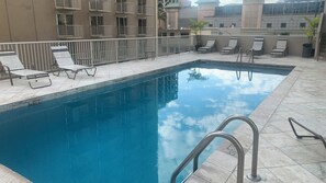 Ein Pool auf dem Dach mit Liegestühlen und einem Metallgeländer.