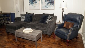 A living room with a sectional sofa, a chaise lounge, a coffee table, and abstract wall art. - Tranquil 2-bedroom townhome with AC in charming Troy (Troy)