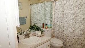 Un bagno con lavandino, specchio, WC e tenda per la doccia.