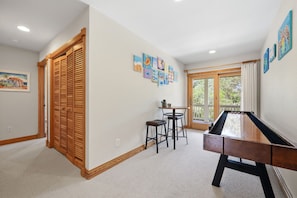 A room with a pool table, a wooden cabinet, and a dining area with chairs. - Spacious 5BR Corolla retreat with private pool, hot tub, and game room. (Corolla)