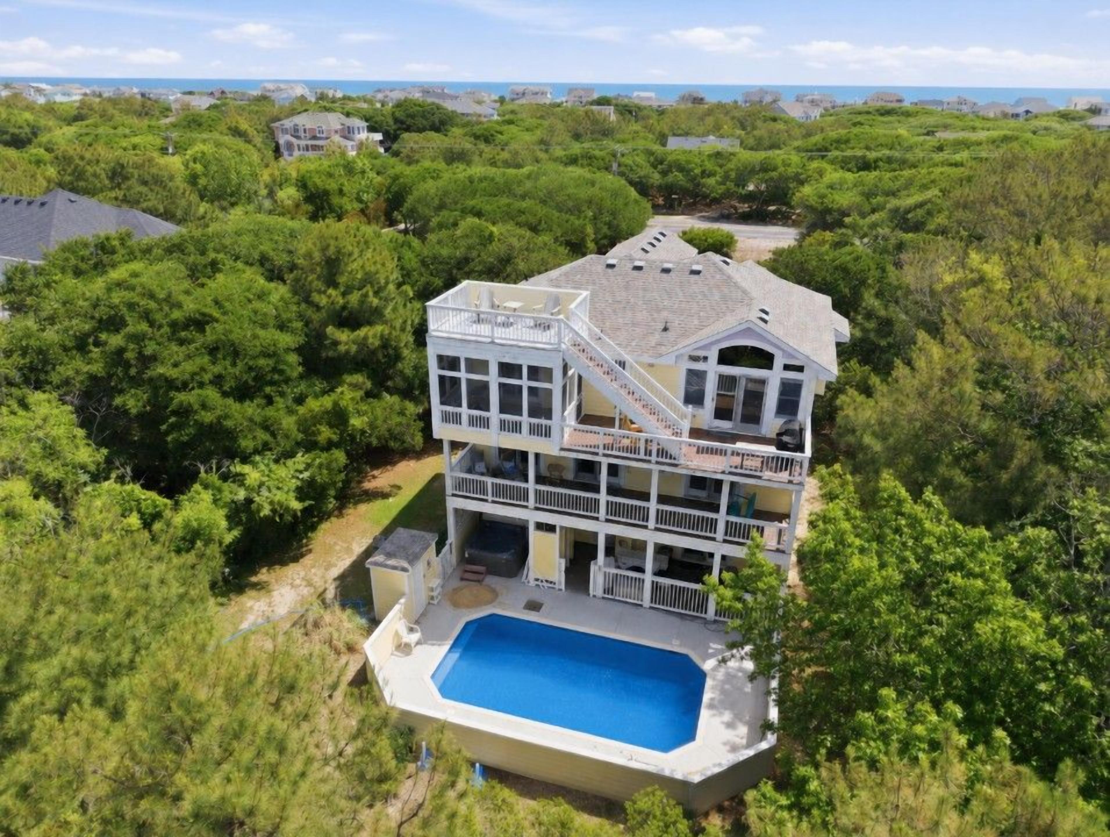 Ein mehrstöckiges Haus mit Schwimmbad, umgeben von üppiger Vegetation.