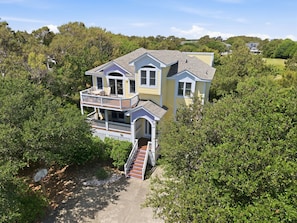A two-story house with a balcony, surrounded by dense greenery. - Spacious 5BR Corolla retreat with private pool, hot tub, and game room. (Corolla)