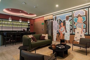 A bar area with stools, a green sofa with cushions, a round coffee table, and a mural with abstract figures. - Gallery-Style Loft, Workspace & Prime Location (Mexico City)