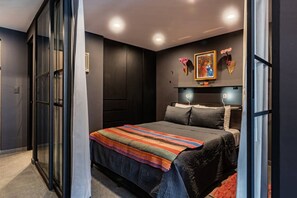 A modern bedroom with a bed, dark walls, and a glass door. - Gallery-Style Loft, Workspace & Prime Location (Mexico City)
