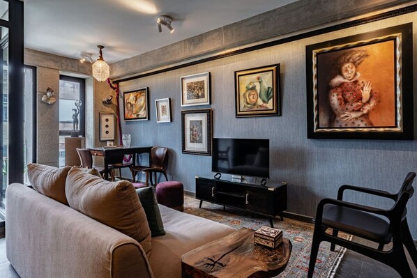 A modern living room with a sofa, chairs, a TV, and artwork on the wall. - Gallery-Style Loft, Workspace & Prime Location (Mexico City)