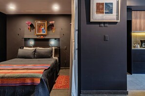 A modern bedroom with a bed, bedside tables, and a nightstand. There is a framed picture on the wall and a small shelf with decorative items. - Gallery-Style Loft, Workspace & Prime Location (Mexico City)