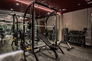 A gym with weightlifting equipment, a bench, and a rack of dumbbells. - Combo Suites: 4BR, Gym, Rooftop & Coworking (Mexico City)