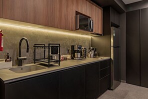 Une cuisine moderne dotée d’un évier en acier inoxydable, d’une machine à café et d’un four à micro-ondes placé au-dessus du plan de travail.