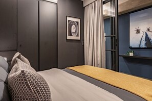A modern bedroom with a bed, pillows, a framed picture, and a window with curtains. - Boutique 1BR Suite Near Reforma (Mexico City)