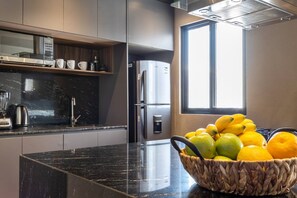 Eine moderne Küche mit schwarzer Arbeitsplatte, Edelstahlgeräten und einer Obstschale.