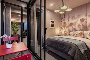A bedroom with a bed, a red table with chairs, and a large window. - Modern Balcony Suite Near Reforma | Gym & Views (Mexico City)
