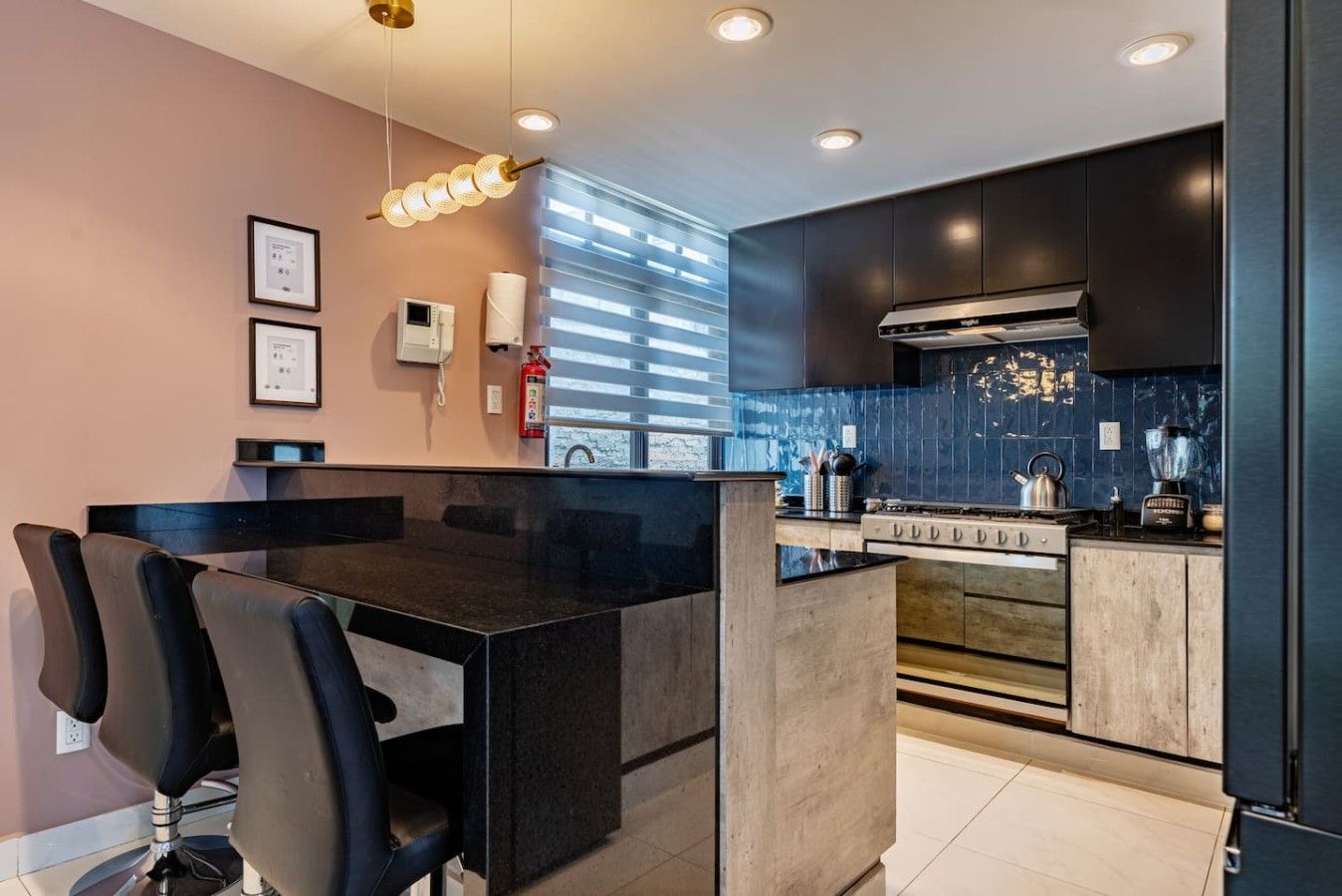 A modern kitchen with a central island, black cabinets, and a stainless steel range hood.