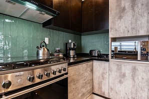 A kitchen with a stainless steel Hobart BOKOMA stove, a coffee maker, and a toaster. - Serene CDMX Stay | Modern (Mexico City)