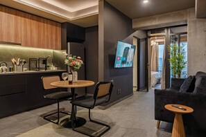 A modern interior with a kitchen area, a dining table with chairs, a sofa, and a TV mounted on the wall. - 3 Private Apartments Near Reforma Tabacalera (Mexico City)