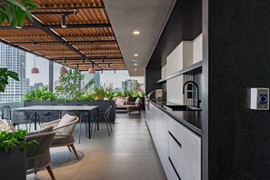 Une cuisine moderne dotée d’un plan de travail noir, d’un four encastré et d’un évier. On y trouve un coin repas avec une table et des chaises, ainsi qu’un coin salon avec un canapé.