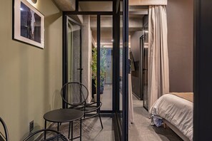 A compact hotel room with a bed, a small table, a chair, and a glass door leading to a balcony. - 3 Private Apartments Near Reforma Tabacalera (Mexico City)