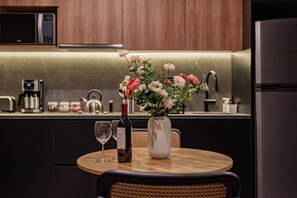 Eine moderne Küche mit Esstisch, Blumenvase, Weinflasche und Kaffeemaschine.