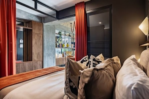 Una habitación de hotel moderna con una cama, una mesita de noche, un ventanal y vistas a la ciudad.