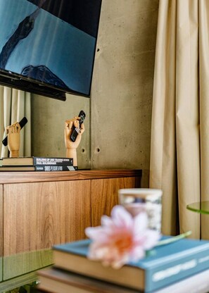A room with a wooden cabinet, a television mounted on a wall, and a window with curtains. - Designer Loft | Rooftop, Gym & Workspace (Mexico City)
