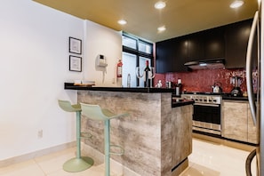 A kitchen with a central island, bar stools, a stove, and a refrigerator. - Retro-Modern Retreat Near Reforma (Mexico City)