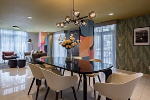 A modern dining area with a glass table, white chairs, and a decorative vase with flowers. - Retro-Modern Retreat Near Reforma (Mexico City)