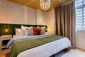A bedroom with a bed, green headboard, white bedding, and a decorative globe light. - Retro-Modern Retreat Near Reforma (Mexico City)