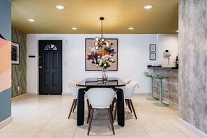 A modern dining area with a round table, chairs, a vase of flowers, and a painting on the wall. - Retro-Modern Retreat Near Reforma (Mexico City)