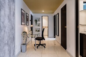 A hallway with a glass table, black office chair, and framed pictures on the walls. - Retro-Modern Retreat Near Reforma (Mexico City)
