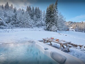 Schneebedeckte Landschaft mit Whirlpool und Picknicktisch.