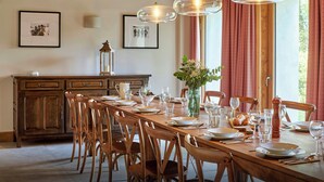 Uma sala de jantar com mesa de madeira posta para seis pessoas, rodeada por cadeiras de madeira.