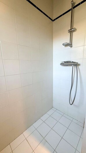 A shower area with white tiled walls and floor, a chrome showerhead, and a handheld showerhead. - Two-story village house in the village of Ars (ARS EN RE)