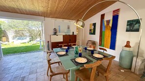 A dining area with a glass table, wooden chairs, and a view of the garden. - Two-story village house in the village of Ars (ARS EN RE)