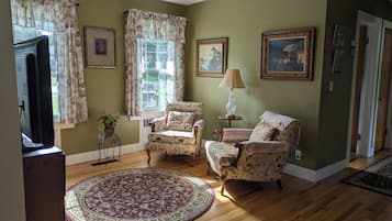 A living room with two armchairs, a round rug, a lamp, and framed artwork on the walls.