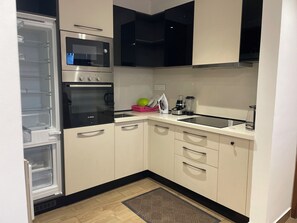 A compact kitchen with a Bosch oven, a microwave, a coffee maker, and a blender on the counter. - Cozy 1-bedroom apartment in beautiful Accra with AC and gym (Accra)