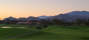 A golf course with a clubhouse, palm trees, and mountains in the background. - Desert Falls Country Club Villa - Remodeled 2BR- Golf, Pickleball, Tennis & Pool (Palm Desert)