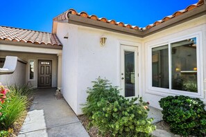 A residential building with a tiled roof, a front door, and a large window. - Desert Falls Country Club Villa - Remodeled 2BR- Golf, Pickleball, Tennis & Pool (Palm Desert)