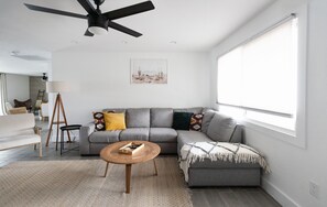 A modern living room with a gray sofa, a wooden coffee table, and a ceiling fan. - Modern Scottsdale/PHX Getaway, Private Heated Pool - Minutes to Golf & Shopping (Phoenix)