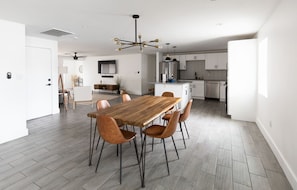 A modern kitchen with white cabinetry, a stainless steel refrigerator, and a dining area with a wooden table and leather chairs. - Modern Scottsdale/PHX Getaway, Private Heated Pool - Minutes to Golf & Shopping (Phoenix)